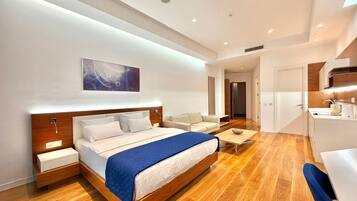 Una habitación de hotel moderna con una cama de madera, una mesita de noche, un escritorio pequeño y una silla.