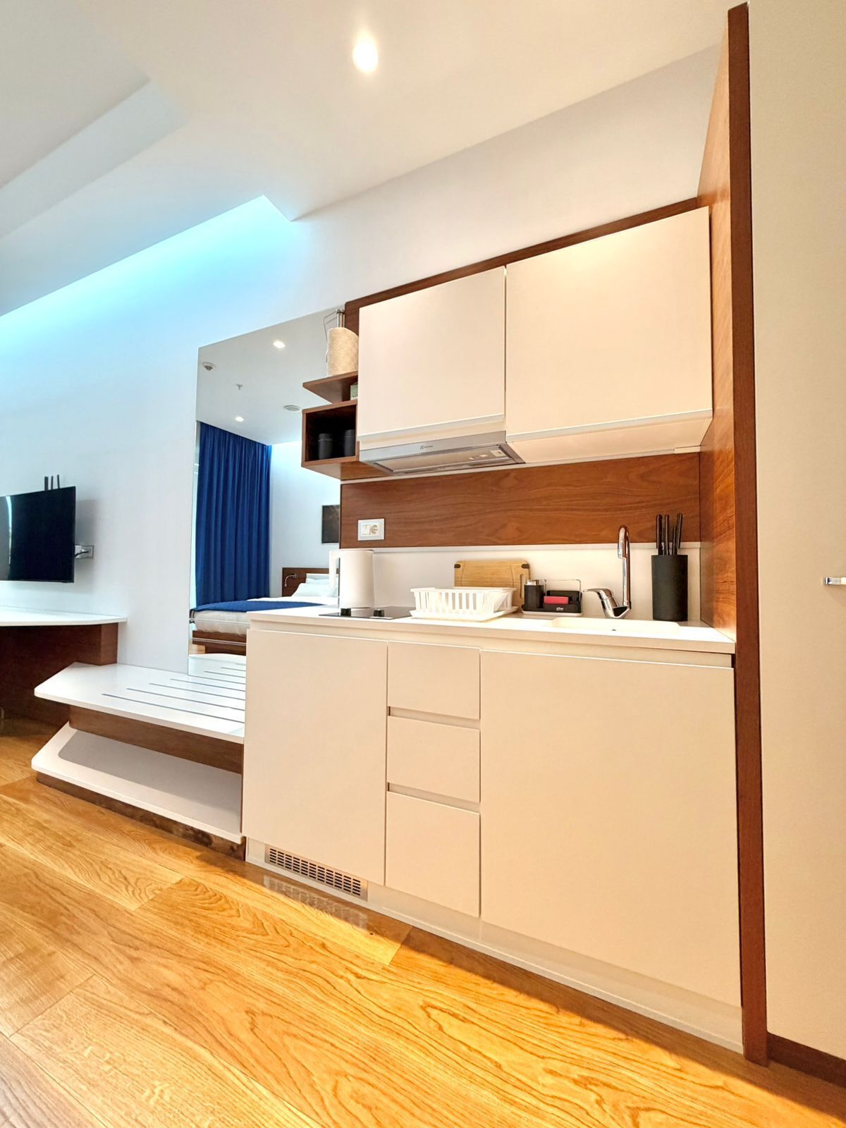 Una cocina moderna con electrodomésticos integrados, un banco empotrado y un televisor de pantalla plana.