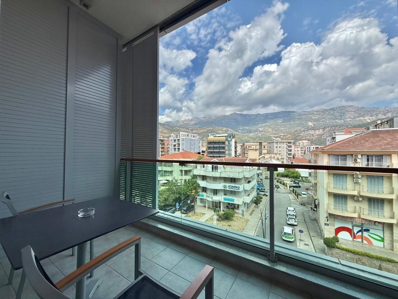 A balcony with a view of a cityscape, including buildings and a pharmacy.