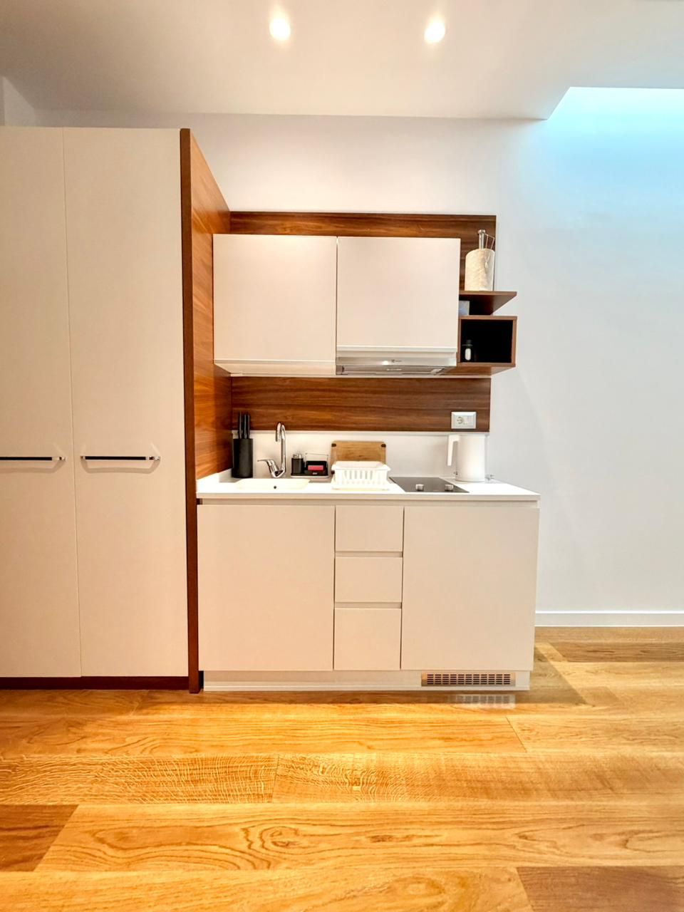 Una cocina moderna con armarios blancos, encimera de madera y horno empotrado.
