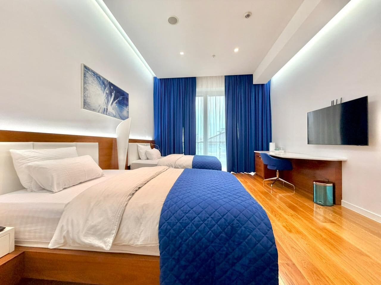 Une chambre d’hôtel moderne, dotée d’un grand lit, d’un bureau et d’une télévision.