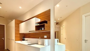 A modern kitchen with white cabinetry, wooden accents, and a built-in bench. - Condo Studio Plaza (Budva)