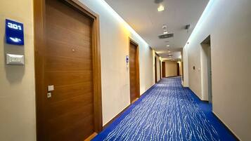 A hotel hallway with a blue carpet, wooden doors, and a sign indicating room number 301.
