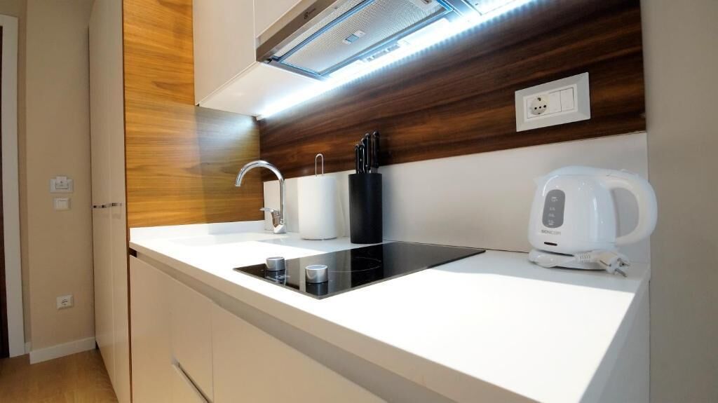 A modern kitchen with a built-in stove, a kettle, and a knife block.