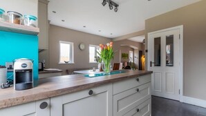 A modern kitchen with a wooden countertop, a coffee maker, and a vase with flowers. - Beautiful 5 bedroom House in smart suburb. Close to beautiful Lake & Parkland. (Cardiff)