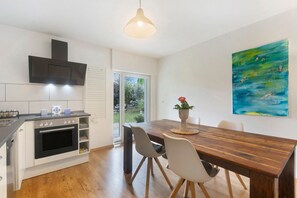 A modern kitchen with a built-in oven, a dining table with chairs, a pendant light, and a painting on the wall. - Apartment 'Am Pieperknapp' with Mountain View, Private Terrace and Wi-Fi (Olsberg)