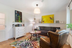 A living room with a sofa, a chair, a coffee table, a white dresser, and artwork on the walls. - Apartment 'Am Pieperknapp' with Mountain View, Private Terrace and Wi-Fi (Olsberg)