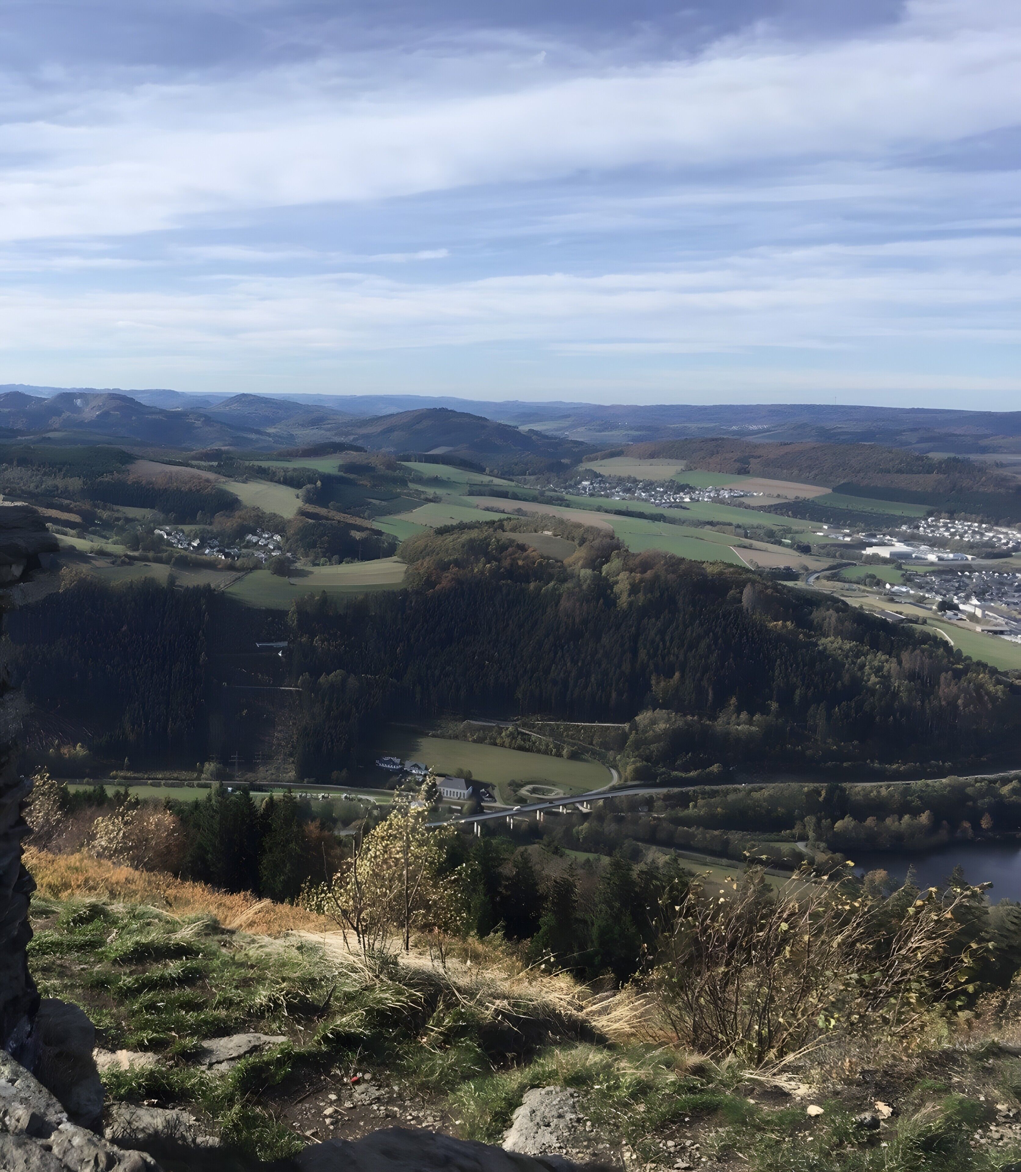 Ein Panoramablick auf ein Tal mit einer kleinen Stadt, sanften Hügeln und einem Fluss.