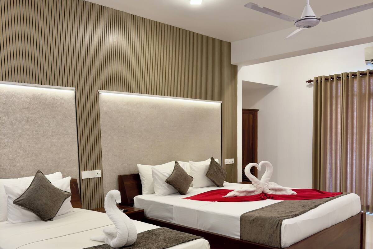 A modern hotel room with two beds, a ceiling fan, and a large mirror.