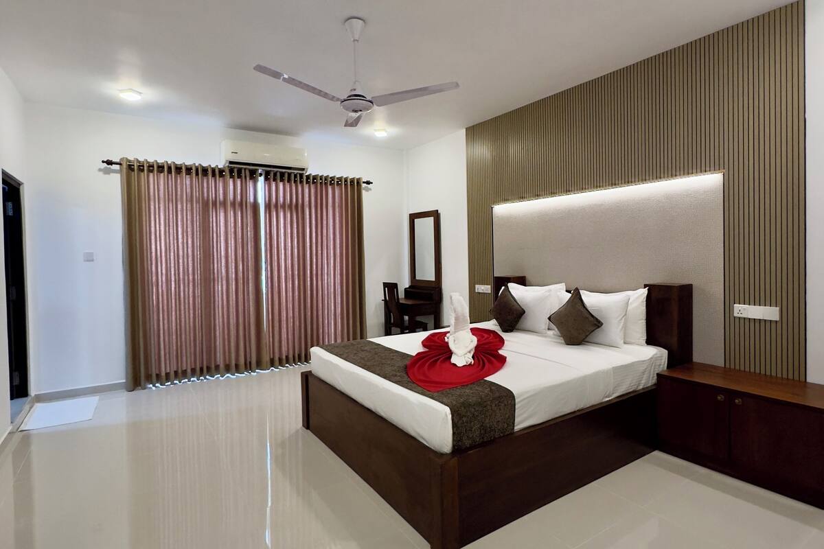 A modern hotel room with a large bed, a ceiling fan, and a built-in headboard.