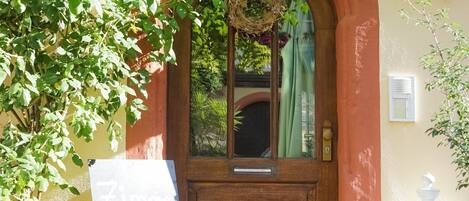 A wooden door with a wreath, a green curtain, and a sign that reads 'Zimmer frei.'