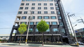 A modern hotel with multiple floors, large windows, and a prominent clock on the facade. - Brown Dot Sports Complex Branch Co., Ltd. (Jecheon)