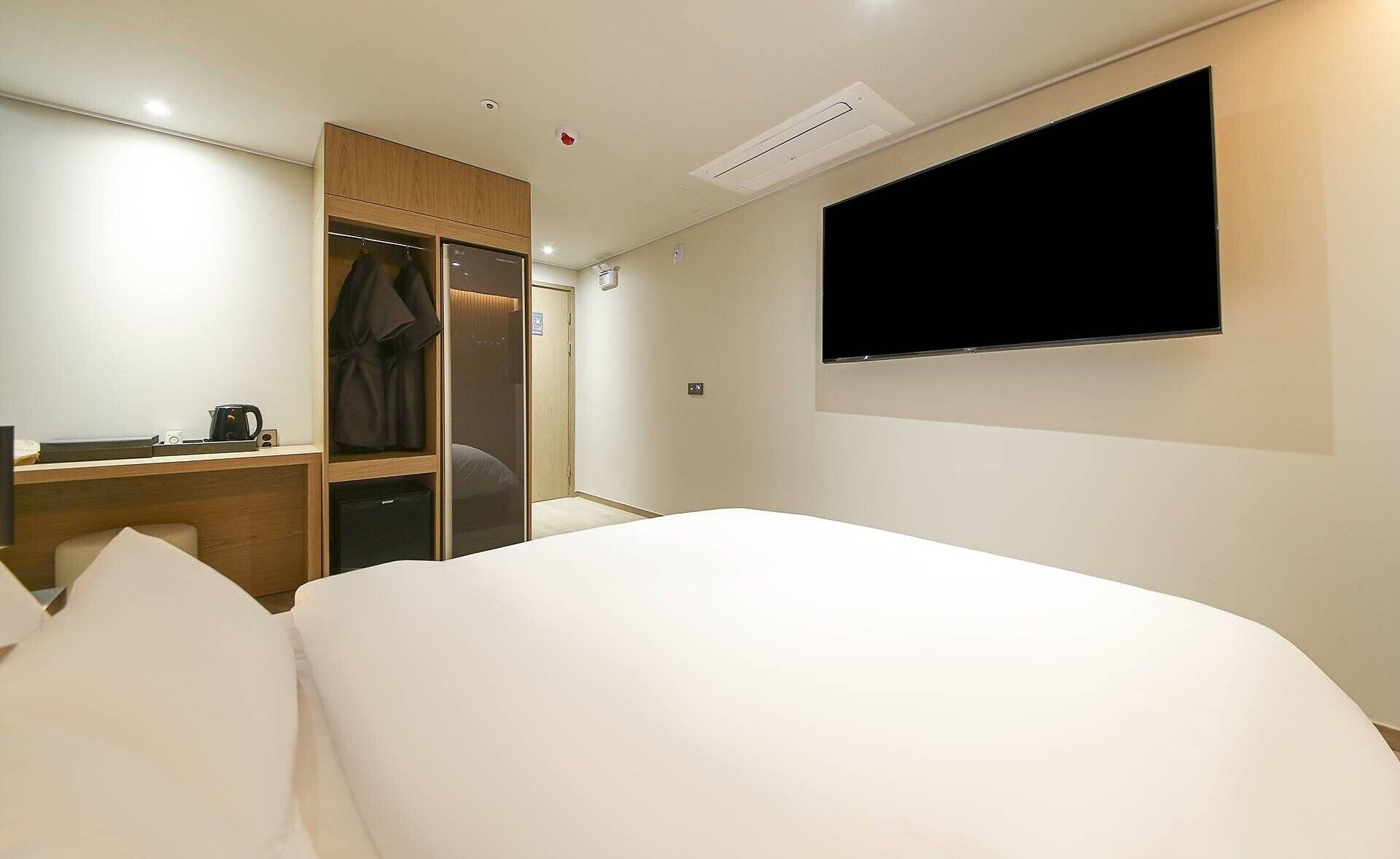 A hotel room with a bed, a desk, a wardrobe, and a TV.