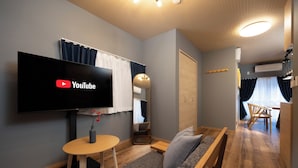 Moderni olohuone, jossa on litteänäyttöinen televisio, sohva, pieni pöytä ja peili.