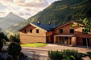 Una casa de ladrillo de dos pisos con techo inclinado, un porche cubierto y montañas al fondo.