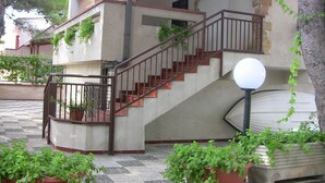 Un edificio de varios niveles con una escalera, plantas en macetas y un farol.