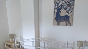 Un dormitorio con una cama, dos mesitas de noche, una lámpara, un cuadro en la pared y una ventana.