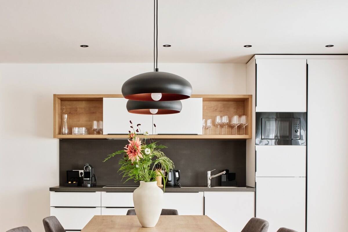 A modern kitchen with white cabinets, a black microwave, and a wooden countertop.