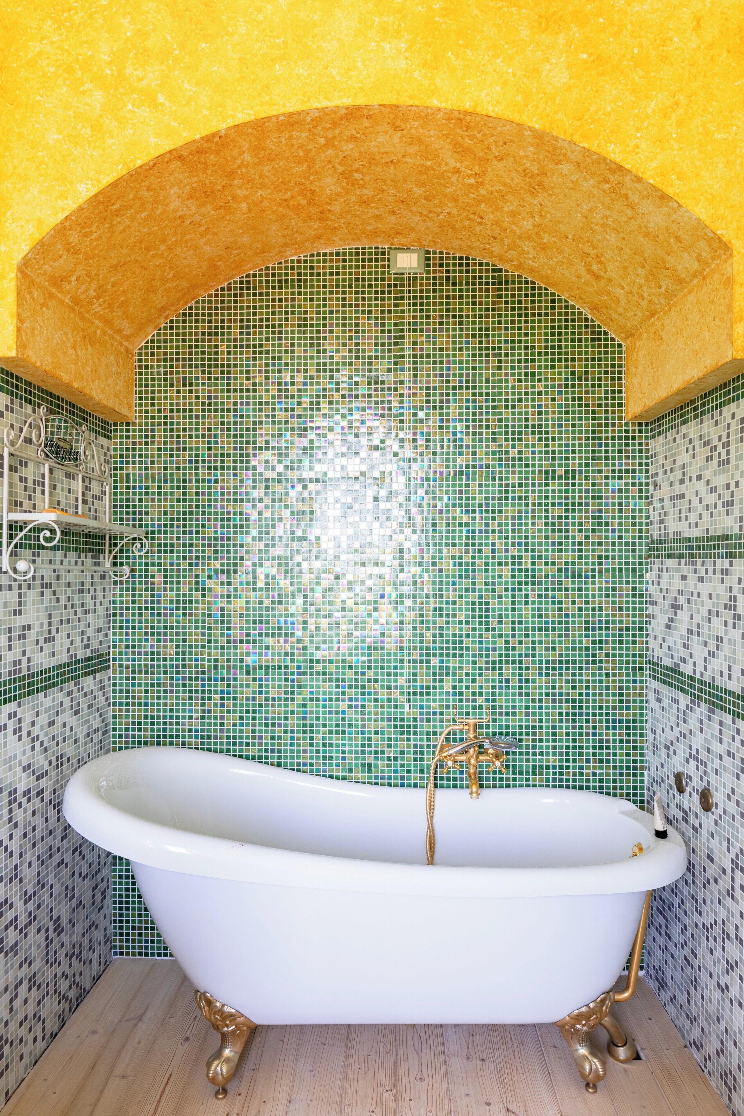 Une baignoire avec un mur recouvert de mosaïques et un plafond en arc de cercle.
