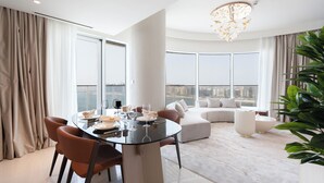 A modern living room with a glass dining table, a sofa, and a large window offering a city view. - KeyRock - Palm & Sea View with Pool (Dubai)