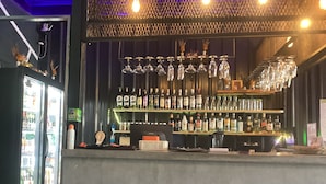 A bar area with shelves of liquor bottles, a refrigerated display case, and hanging wine glasses. - SongKler (Ko Pha-ngan)