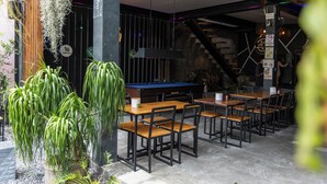 An indoor dining area with wooden tables and chairs, a pool table, and hanging plants. - SongKler (Ko Pha-ngan)
