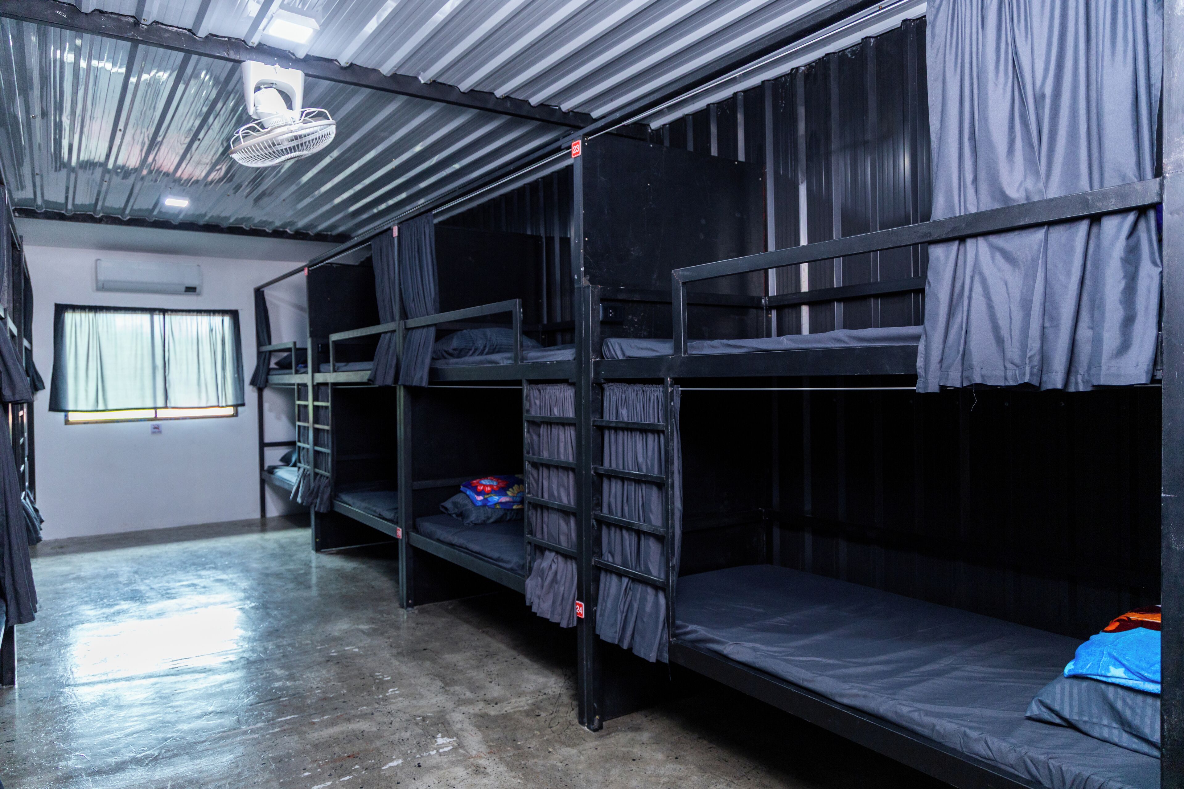 Un dormitorio con literas, ventilador de techo y ventana con cortinas.