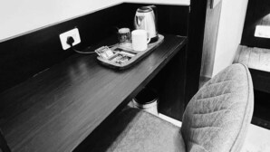 A small, dark wooden desk with a chair, a kettle, a mug, and a tray with a newspaper. - Sky Suites By Glitz Hotels (Mumbai)