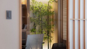 A room with a chair, a small table, and a bamboo plant.