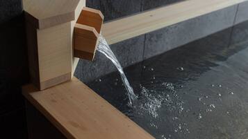 A wooden water feature with water flowing into a stone basin.