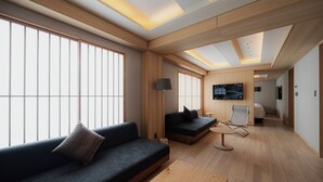 A modern hotel room with a sofa, a small table, and a TV.