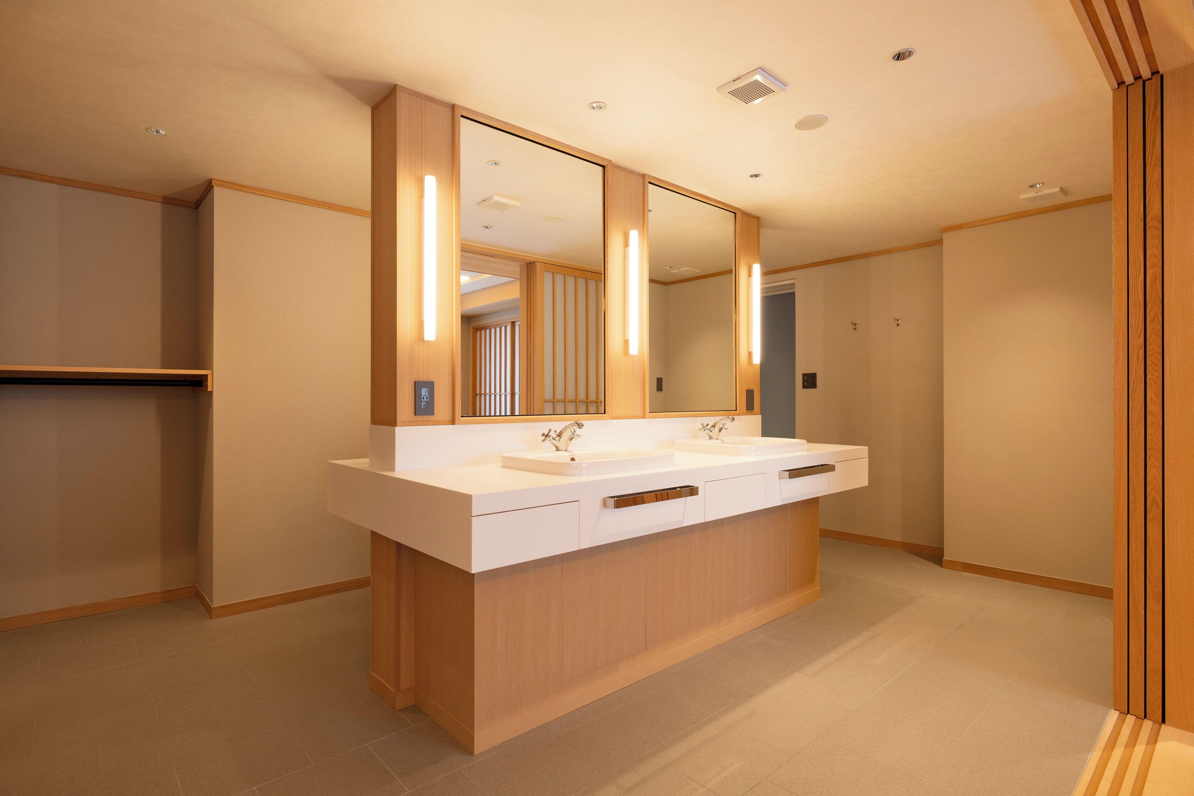 A modern bathroom with a large mirror, two sinks, and wooden cabinetry.