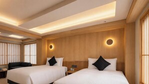 A hotel room with two beds, a sofa, a small table, and a traditional Japanese shoji screen.