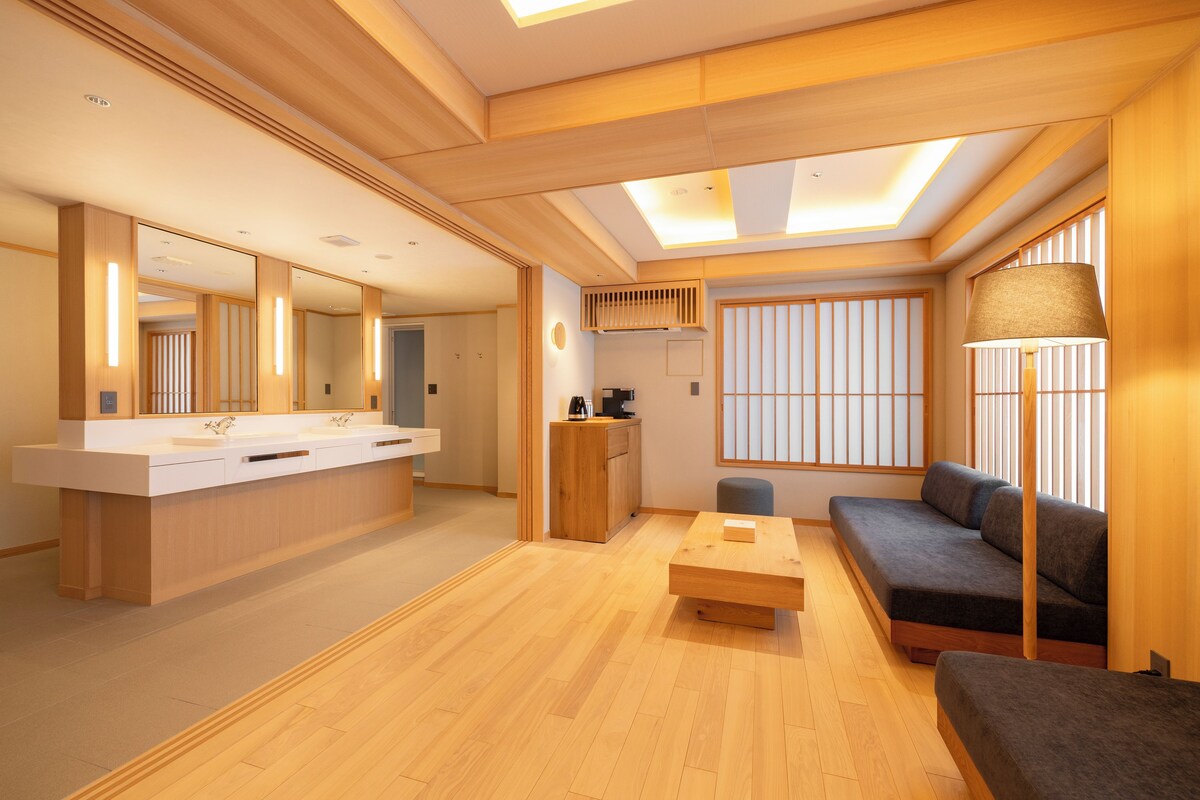 Un interior moderno con piso de madera, un sofá, una mesita de centro y un espejo grande.