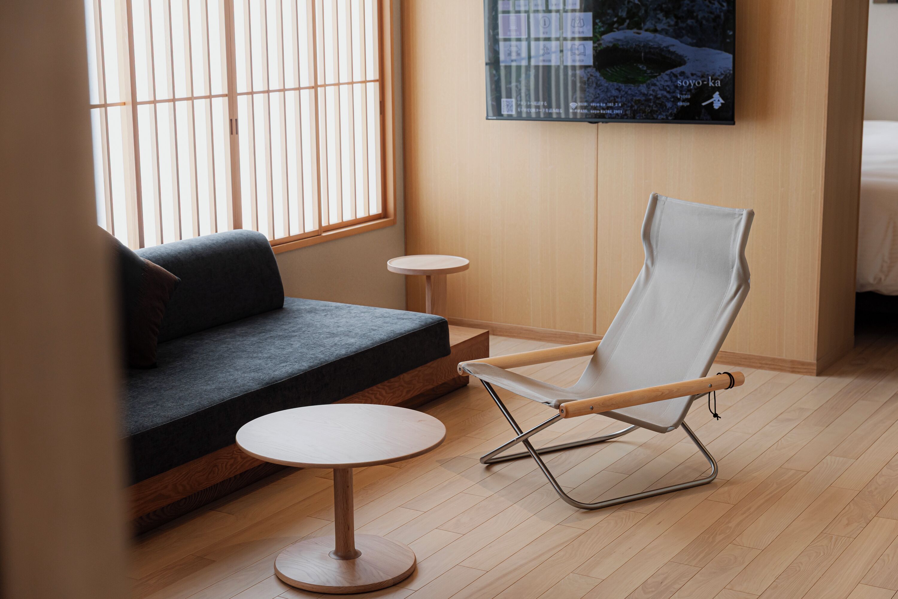 A modern room with a sofa, a small round table, and a lounge chair.