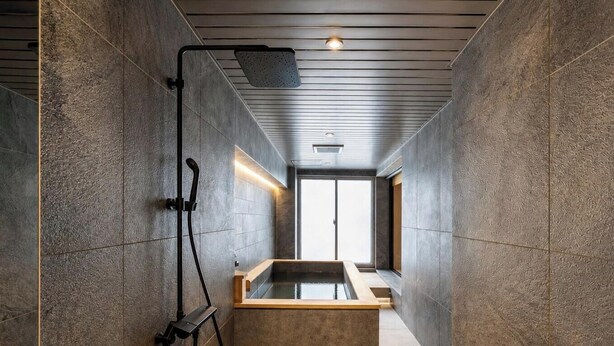 A modern bathroom with a large bathtub, a showerhead, and a window providing natural light.