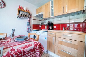 Cozinha com armários de madeira, lava-louças e backsplash de azulejos vermelhos.