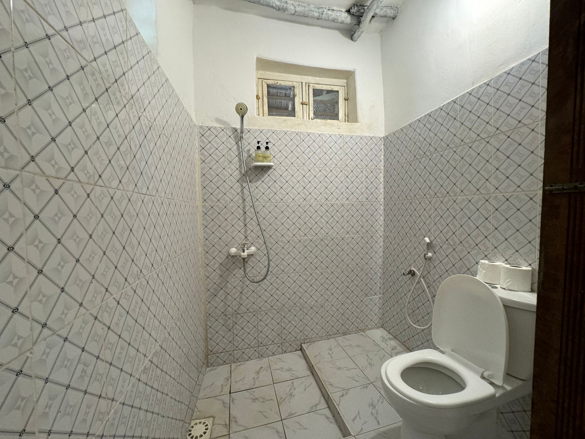 Ein Badezimmer mit Toilette, Dusche und einem Fenster.