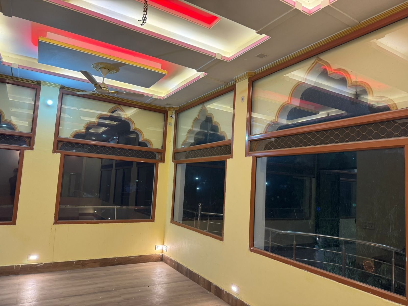 Una habitación de hotel con ventanas amplias, un ventilador de techo y una lámpara moderna.
