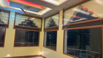 Una habitación de hotel con ventanas amplias, un ventilador de techo y una lámpara moderna.