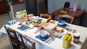 A breakfast table set with various food items, including bread, fruit, and condiments. - Chambre 2 lit simple avec balcon (Lézignan-Corbières)