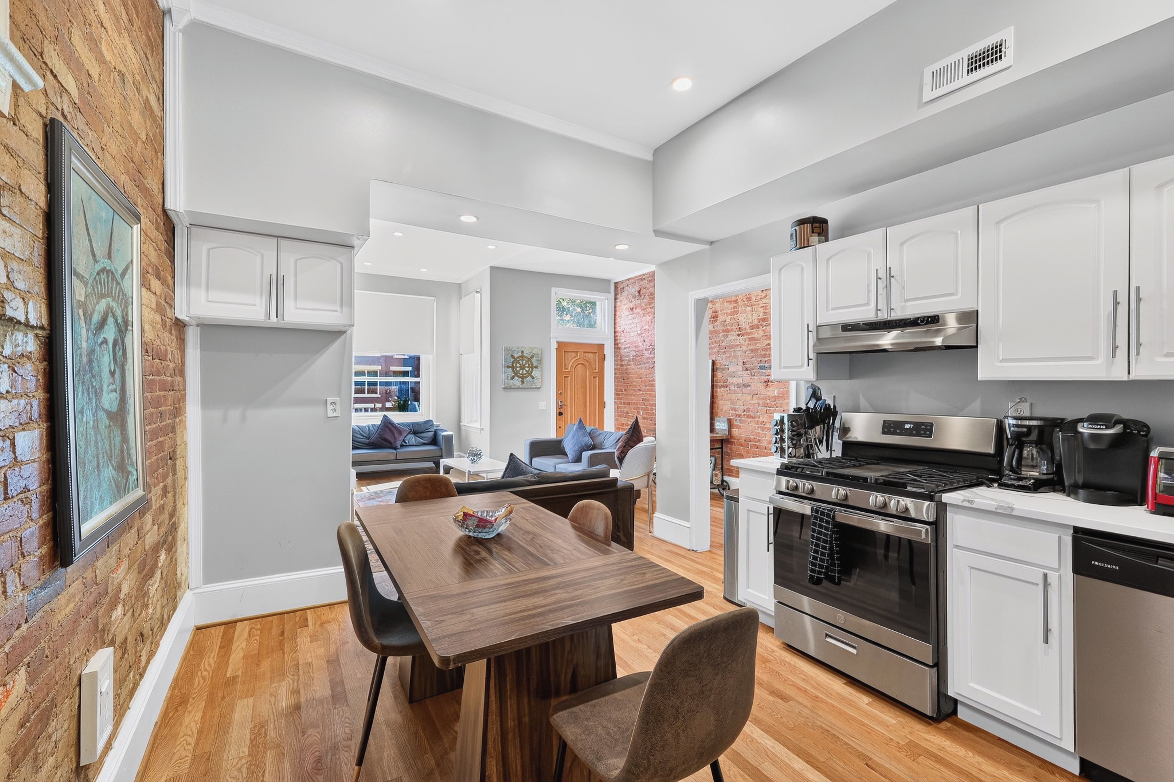 A modern kitchen with white cabinets, a built-in oven, and a coffee maker.
