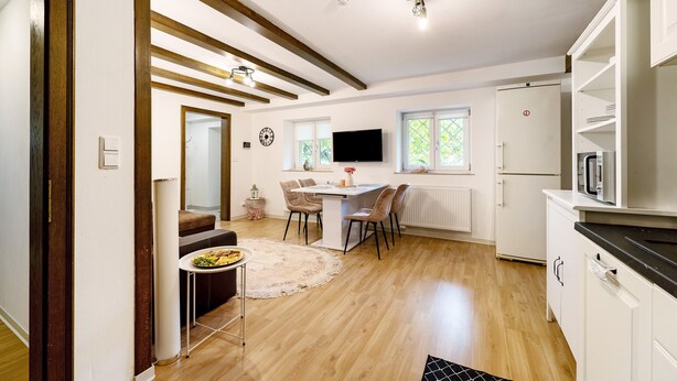 A modern kitchen with white cabinets, a dining area with a table and chairs, and a built-in TV. - Apartment 'Green House' with Private Terrace, Private Garden and Wi-Fi (Neunkirchen)