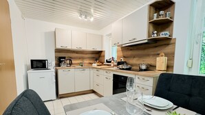 A modern kitchen with a microwave, coffee maker, and wooden shelves. - Apartment 'Pleißennest' with Wi-Fi (Chemnitz)