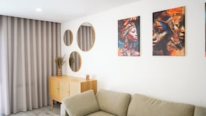 Un salon comprenant un canapé, un meuble en bois et trois miroirs fixés au mur.