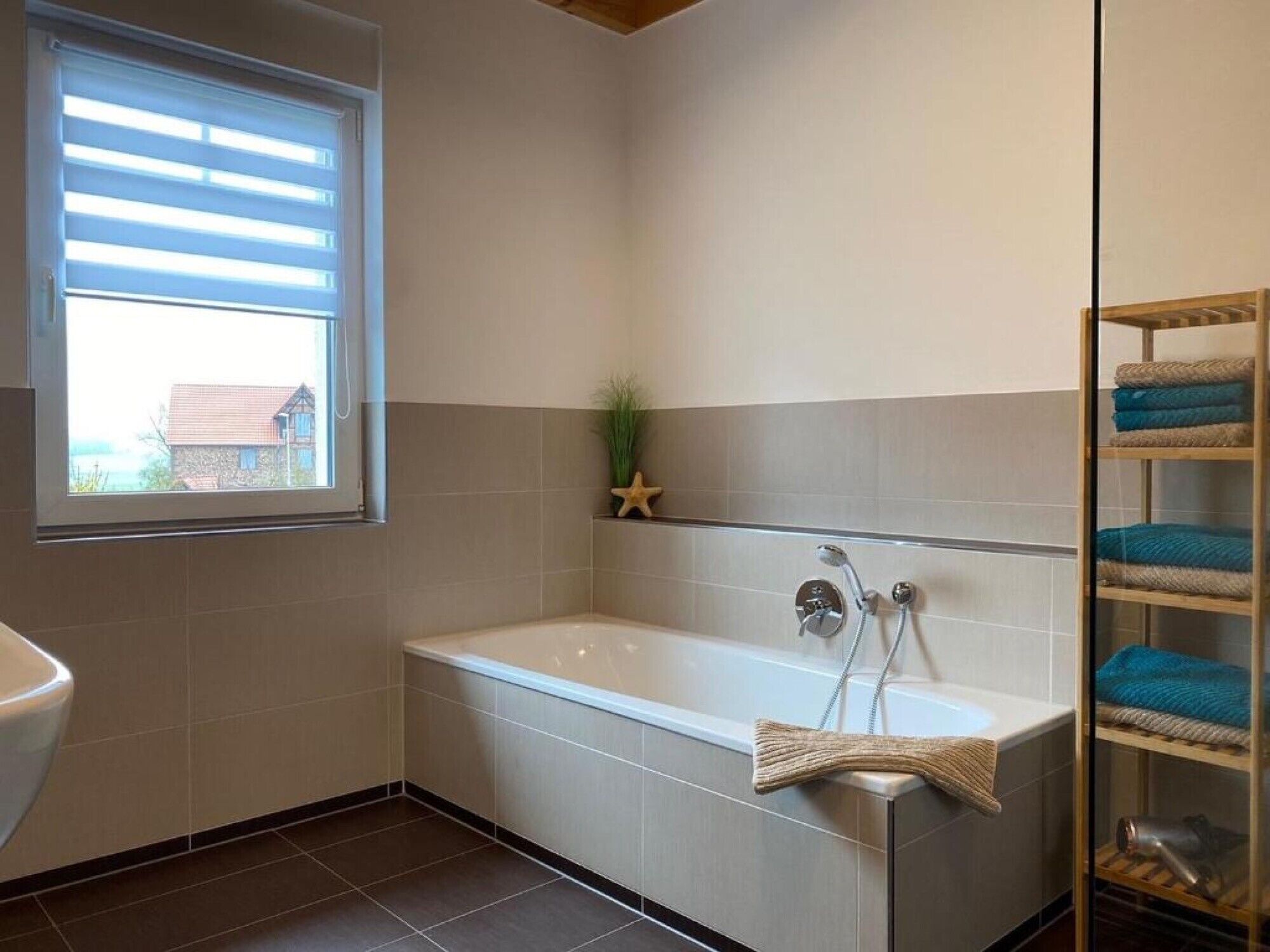Un bagno con una vasca, una finestra e un porta asciugamani.