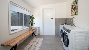 A laundry room with a washing machine, a bench, a window, and a door.