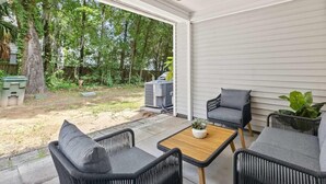 A covered patio with wicker furniture, a ceiling fan, and a view of a backyard with trees and a grill. - Queen Kelsey-Mins From Credit One-Pet Friendly (Charleston)