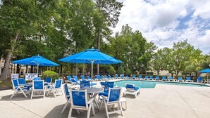A poolside area with blue umbrellas, white lounge chairs, and a sign indicating no lifeguard on duty. - Queen Kelsey-Mins From Credit One-Pet Friendly (Charleston)