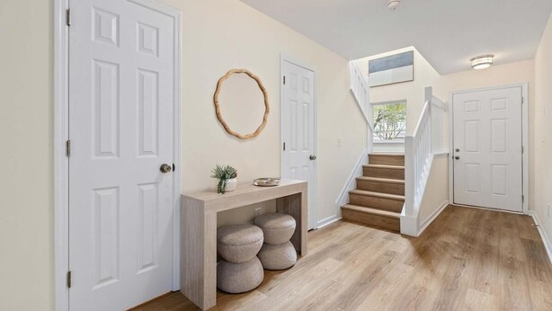 A hallway with white doors, a wooden console table with a small plant, and a staircase leading to another room. - Queen Kelsey-Mins From Credit One-Pet Friendly (Charleston)